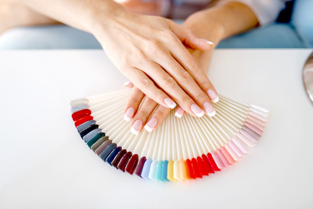 Manos mostrando paletas de colores para uñas